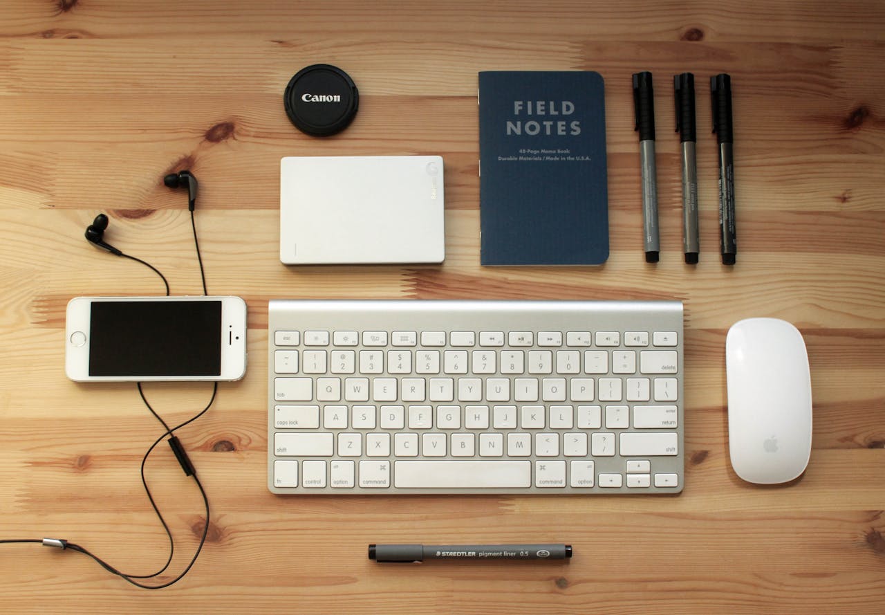 services-img Top view of a modern desk setup featuring electronics, stationery, and gadgets on a wooden surface.